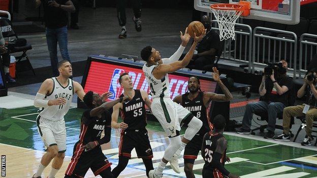 Giannis Antetokounmpo impulsa hacia la canasta contra el alero de Miami Heat Trevor Ariza (8) y el base Duncan Robinson (55) en el primer cuarto durante el segundo juego en la primera ronda de los Playoffs de la NBA de 2021