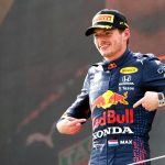 Max Verstappen señala el logo de Red Bull mientras celebra la victoria del GP de Austria.  Julio de 2021.