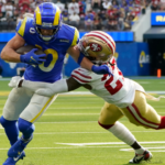 El back defensivo de los 49ers de San Francisco, Dontae Johnson (27), aborda al receptor abierto de los Rams de Los Ángeles, Cooper Kupp (10), durante la primera mitad de un partido de fútbol americano de la NFL el domingo 9 de enero de 2022 en Inglewood, California.