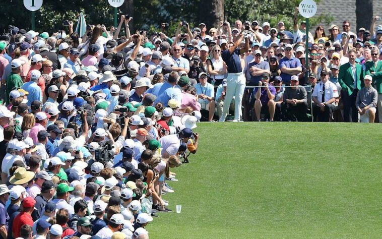 Espectadores ven al cinco veces campeón del Masters Tiger Woods dar el primer golpe durante una ronda de práctica para el Masters en Augusta National Golf Clu - AP