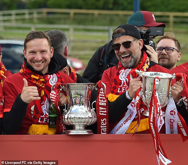 El jefe del Liverpool, Jurgen Klopp (derecha), era todo sonrisas mientras acunaba la Copa FA y la Copa Carabao.