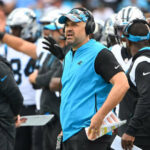 Matt Rhule mira hacia el campo desde la banca durante un juego de los Panthers