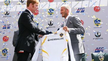 El entonces presidente del LA Galaxy, Alexi Lalas, le entrega a David Beckham su camiseta durante una conferencia de prensa que presenta a Beckham como el nuevo fichaje del club el 13 de julio de 2007.