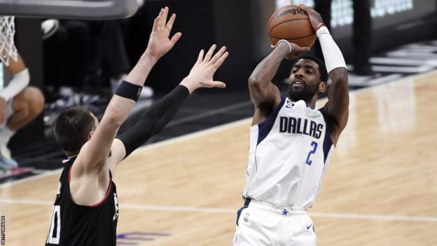 Kyrie Irving (derecha) realiza un tiro en suspensión durante su debut con los Dallas Mavericks