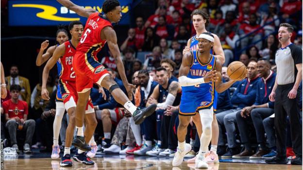 El guardia del Oklahoma City Thunder, Shai Gilgeous-Alexander, pasa el balón contra el delantero de los New Orleans Pelicans, Herbert Jones.