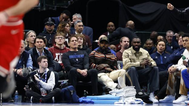 El propietario de los Dallas Mavericks, Mark Cuban, Kyrie Irving y Tim Hardaway Jr. observan el partido de los Chicago Bulls junto a la cancha