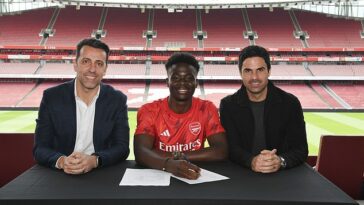 Bukayo Saka posa junto al director deportivo del Arsenal, Edu (izquierda) y el entrenador Mikel Arteta (derecha) después de firmar un contrato de £ 300,000 por semana hasta 2027