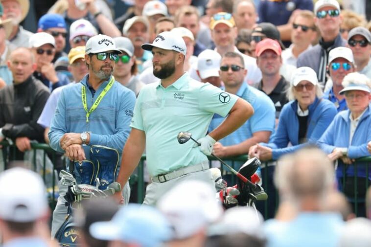 El campeón reinante de Masters mejor clasificado, Jon Rahm, en el centro, espera junto al caddie Adam Hayes durante una ronda de práctica en Oak Hill para el 105.° Campeonato de la PGA.