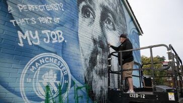 El artista Murwalls, también conocido como Marc Silver (en la foto), repara un vandalismo en el mural de Pep Guardiola fuera del estadio Etihad.