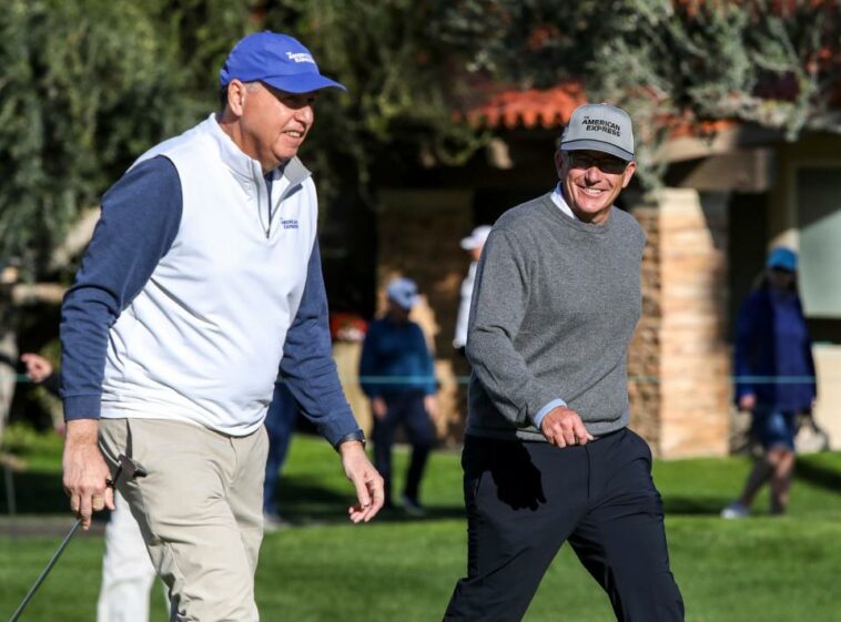 El comisionado del PGA Tour, Jay Monahan, sonríe al director ejecutivo de American Express, Stephen Squeri, mientras se acercan al segundo green durante la primera ronda del torneo de golf The American Express en La Quinta Country Club en La Quinta, California, el jueves 19 de enero de 2023.