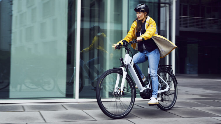 Una mujer monta una bicicleta eléctrica por una ciudad.