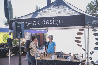 Dos mujeres conversan en la carpa de la exposición Peak Design en Roam Fest 2023.