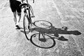 Empujando una bicicleta de carretera por una carretera asfaltada