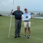 Bentley Van Pelt (derecha), del oeste de Florida, recibe la bandera del campeonato de manos del director ejecutivo de First Tee Gulf Coast, Marty Stanovich (izquierda), en el green 18 del Pensacola Country Club después de ganar la 15.ª edición anual de la Copa A. Downing Gray el martes 30 de julio de 2024.
