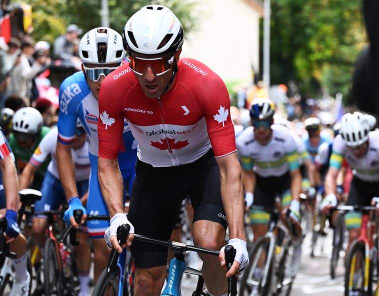 Michael Woods captado por la cámara comiendo gel de bicarbonato con una cuchara durante la carrera en ruta del Campeonato Mundial