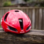 Un casco aerodinámico Kask Utopia Y rojo se asienta sobre un banco de madera