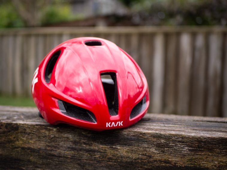 Un casco aerodinámico Kask Utopia Y rojo se asienta sobre un banco de madera