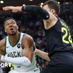 Giannis Antetokounmpo holds the ball as Walker Kessler defends