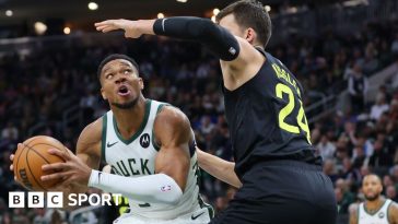 Giannis Antetokounmpo holds the ball as Walker Kessler defends