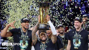 Damian Lillard lifts the NBA Cup while his Milwaukee Bucks team-mates celebrate