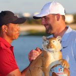 El anfitrión Tiger Woods le da la mano al ganador Scottie Scheffler en el evento Hero World Challenge 2024, junto al trofeo del torneo.