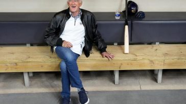 Bob Uecker, locutor jugada por jugada de los Cerveceros de Milwaukee, se sienta en el dugout durante un entrenamiento en American Family Field en Milwaukee el miércoles 6 de abril de 2022. Uecker falleció la madrugada del jueves 16 de enero de 2025 en su casa a la edad de 90.