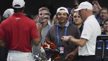 Charlie Woods observa a su padre Tiger calentar antes de un partido contra el Los Angeles Golf Club, el martes 14 de enero de 2025, en Palm Beach Gardens, Florida. TGL presentó dos equipos de tres jugadores compitiendo entre sí en una arena repleta de tecnología. del tamaño de un campo de fútbol. (Foto AP/Marta Lavandier)