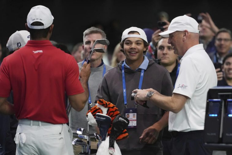 Charlie Woods observa a su padre Tiger calentar antes de un partido contra el Los Angeles Golf Club, el martes 14 de enero de 2025, en Palm Beach Gardens, Florida. TGL presentó dos equipos de tres jugadores compitiendo entre sí en una arena repleta de tecnología. del tamaño de un campo de fútbol. (Foto AP/Marta Lavandier)