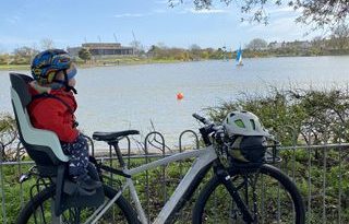 niño sentado en un asiento de bicicleta para niños montado en un portaequipajes mirando a los patos