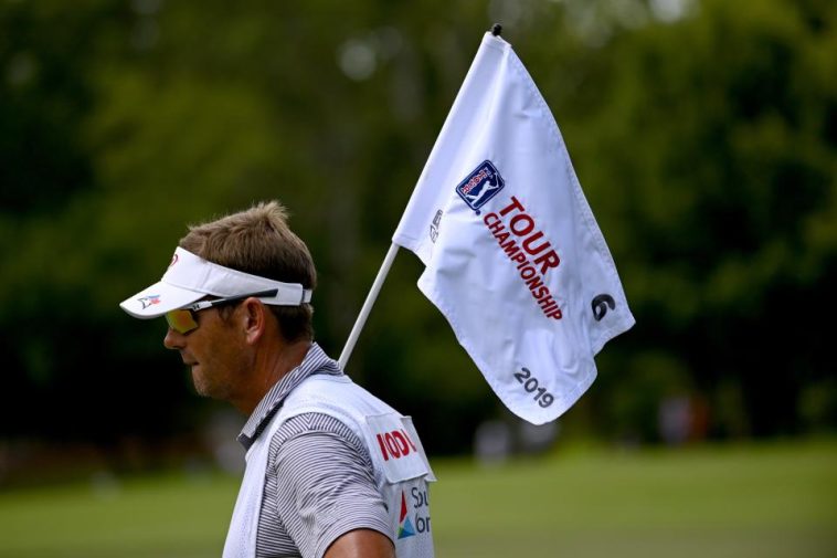 El Caddy para Gary Woodland sostiene la bandera del PIN en el sexto hoyo durante la segunda ronda del Campeonato Tour 2019 en East Lake Golf Club.