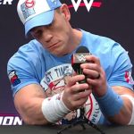 John Cena en una conferencia de prensa, sosteniendo un micrófono.