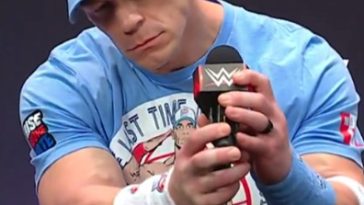 John Cena en una conferencia de prensa, sosteniendo un micrófono.